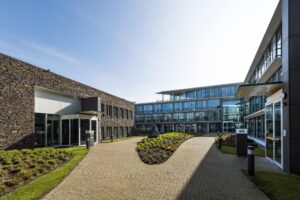 Modern kantoorgebouw aan de De Cuserstraat met glazen gevels en een verzorgde binnentuin.